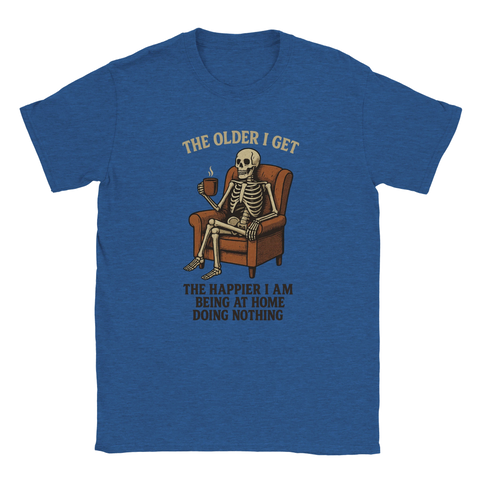 T-shirt med illustration av ett skelett som sitter i en fåtölj med en kaffekopp, tillsammans med texten "The Older I Get The Happier I Am Being At Home Doing Nothing". Perfekt humortröja för soffpotatisar och livsnjutare.