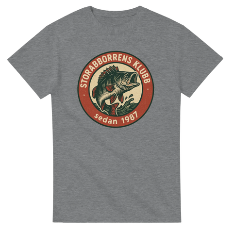 Grå fiske-tshirt med vintage badge och en tecknad stor abborre, samt texten "Storabborrens Klubb – sedan 1987", perfekt för sportfiskare