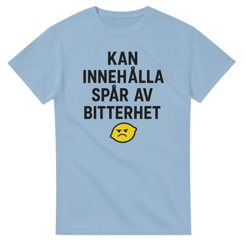 Ljusblå t-shirt med texten "KAN INNEHÅLLA SPÅR AV BITTERHET" och sur citronillustration