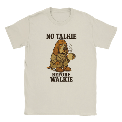 Beige t-shirt med en trött tecknad hund i morgonrock, som håller en kaffekopp och texten "No Talkie Before Walkie" – perfekt för morgontrötta