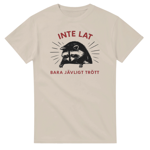 Grafiskt motiv av utmattad tvättbjörn på en beige t-shirt