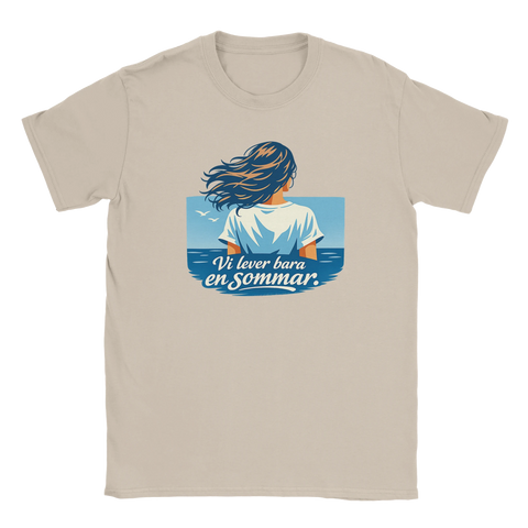 Kvinna med blåsigt hår vid havet, text "Vi lever bara en sommar", på beige t-shirt.