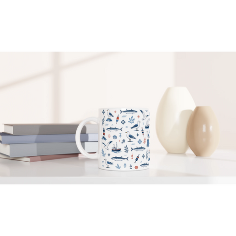 Kaffemugg med västkustmotiv placerad på bord bredvid böcker och vaser