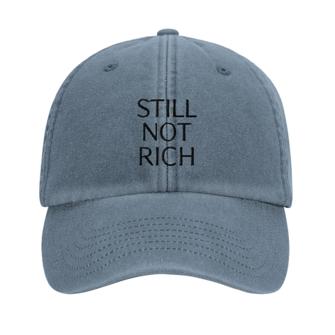 Still Not Rich" svart text på urtvättad blå dad cap, framifrån.