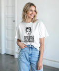 Kvinna bär vit t-shirt med grafiskt porträtt och feministiskt citat