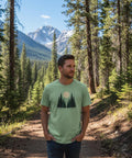 Minimalistiskt skogsmotiv med tre granar och fullmåne på ljusgrön ekologisk t-shirt.
