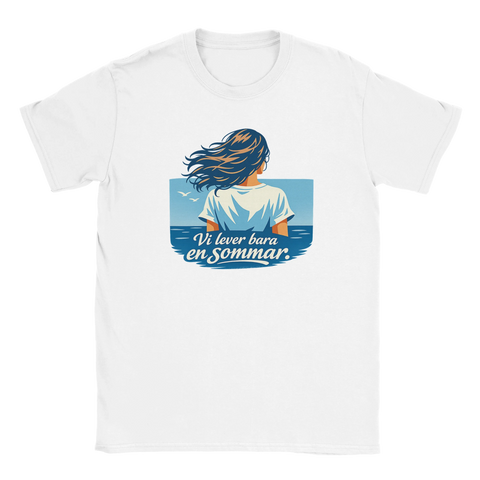 Kvinna med vindblåst hår vid havet, text "Vi lever bara en sommar" på vit t-shirt.