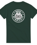 Vitt emblem med burger och text "BURGER DET BLIR LA GÖTT!" på mörkgrön t-shirt.