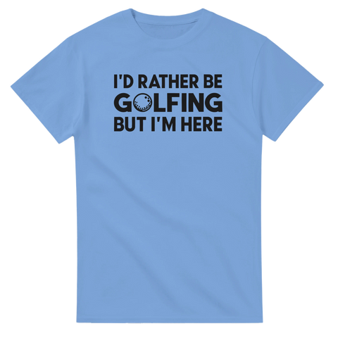 Text "I'D RATHER BE GOLFING BUT I'M HERE" med golfboll, svart tryck på ljusblå t-shirt.