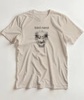 Detaljerad tecknad strutsansikte med text "bird nerd" på beige t-shirt.