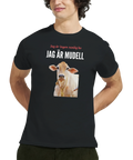Man som bär en svart t-shirt med det roliga ko-trycket Jag är mudell