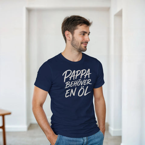 Man bär en marinblå t-shirt med texttryck om pappas behov av öl