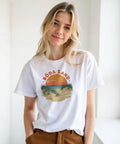 Kvinna bär vit t-shirt med nostalgiskt grafiskt Böda Sand-motiv