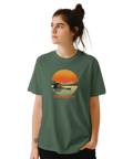 Kvinna bär grön t-shirt med stämningsfullt grafiskt tryck av en sommarstuga