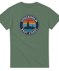 Stockholm East Coast retro-tryck med stadssiluett och solnedgång på grön t-shirt.