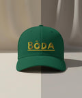 Texten "BÖDA" i gul 3D-stil med linje under på grön truckerkeps.