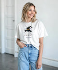 Kvinna bär en vit t-shirt med ett sött spökmotiv och häxhatt