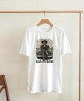 Grafisk t-shirt med retro bil och skelett-motiv hängande på galge