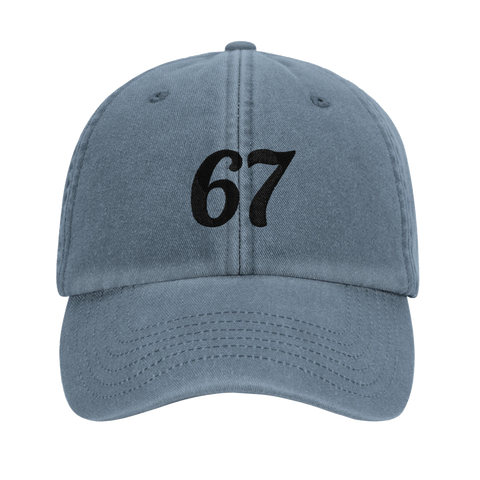 Svart kursiv text "67" på en urtvättad blå dad cap, framifrån.