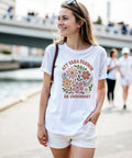 Leende kvinna utomhus i vit t-shirt med grafiskt blomtryck