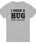 I NEED A HUG FROM A BAD BOY" text i sliten svart stil på grå t-shirt.