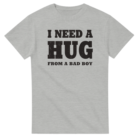I NEED A HUG FROM A BAD BOY" text i sliten svart stil på grå t-shirt.