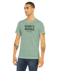 Shirty Works EST. 2025" svart text på mintgrön triblend t-shirt.