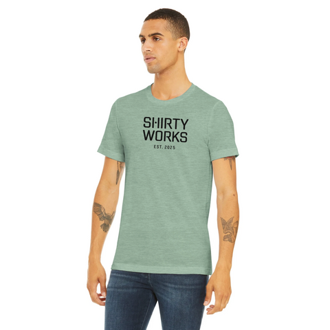 Shirty Works EST. 2025" svart text på mintgrön triblend t-shirt.