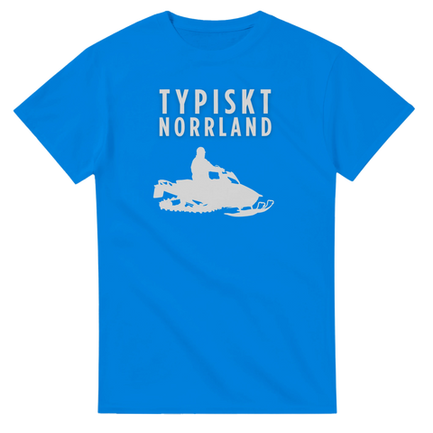 Snöskoter med förare och texten "TYPISKT NORRLAND" i vitt tryck på en klarblå t-shirt.