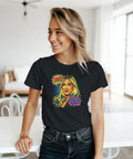 Leende kvinna bär svart t-shirt med färgstarkt pop art-motiv i hemmiljö