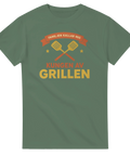 Grillkung-tryck med korsade grillspadar, stjärnor och text på olivgrön t-shirt.