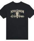 Svart t-shirt med texten Stockholm, ett krönt ansikte och stadssiluett.