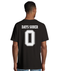 Man bär svart t-shirt med ett provocerande Days Sober-motiv på ryggen