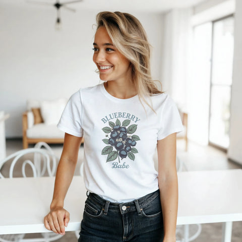 Leende kvinna bär vit t-shirt med lekfullt och naturinspirerat blåbärsmotiv
