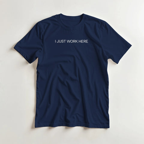 I Just Work Here" texttryck i vit sans-serif på marinblå t-shirt.