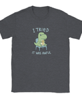 Dinosaurie med "Meh" medalj och text "I tried it was awful" på mörkgrå t-shirt.