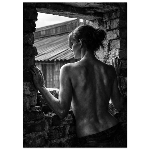 Sensuell fotokonst på en kvinna vid en tegelvägg med naturligt ljusinsläpp som framhäver kroppens linjer.