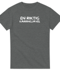 En riktig kärringjävel" texttryck i vitt, bubbligt typsnitt på mörkgrå t-shirt.