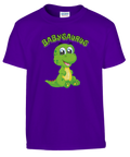 Tecknad grön babysaurus med stora ögon och text "BABYSAURUS" på lila barn-t-shirt.