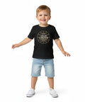 Leende pojke bär en svart t-shirt med det lekfulla motivet Lilla Chefen