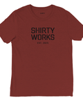 Shirty Works EST. 2025" texttryck i svart på rödbrun triblend t-shirt.