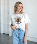 Svart katt med text "TELL YOUR CAT I SAID PSPSPS" på vit t-shirt, retro regnbågsbakgrund.