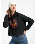 Kvinna bär svart croppad hoodie med mystiskt och lekfullt grafiktryck
