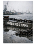 Närbild på en grå betongkaj med texten GÖTEBORGS HAMN, rostiga järnkedjor och lyftkranar i bakgrunden vid mulet väder.