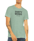 Svart "SHIRTY WORKS EST. 2025" text på mintgrön triblend t-shirt.