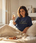 Kvinna i sängen med champagneglas bärande marinblå oversized t-shirt