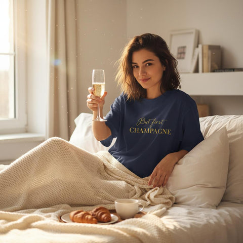 Kvinna i sängen med champagneglas bärande marinblå oversized t-shirt