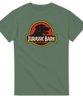 Jurassic Bark logga med svart hundprofil i röd cirkel, text "Jurassic Bark" på olivgrön t-shirt.