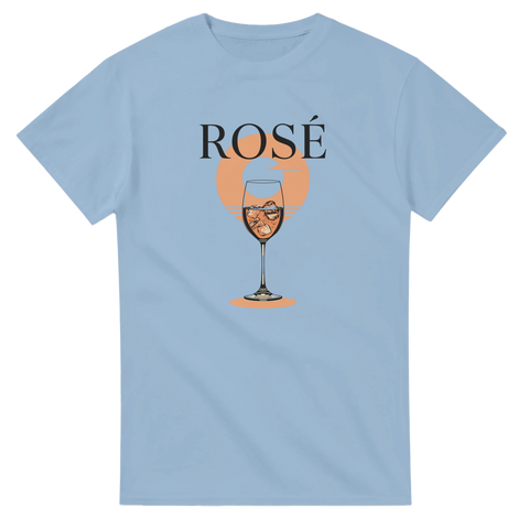 Rosévin i glas med is, orange solnedgång, svart text "ROSÉ" på ljusblå t-shirt.
