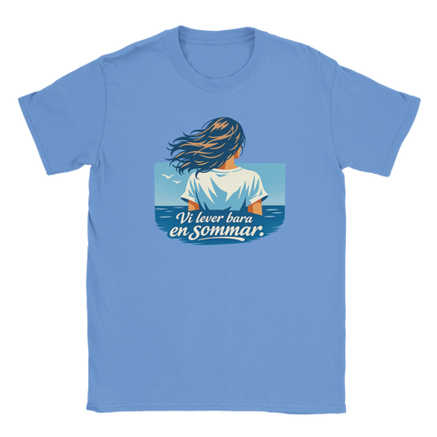 Kvinna med blåsande hår vid havet, text "Vi lever bara en sommar" på ljusblå t-shirt.